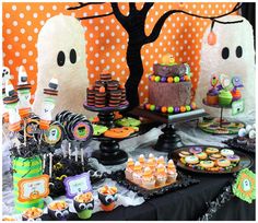 a table topped with lots of candy and halloween decorations on top of a black table cloth