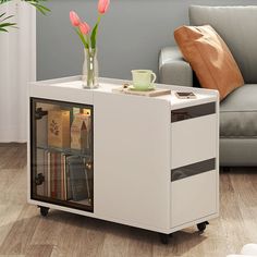 a coffee table with a glass door and some flowers in the vase on top of it