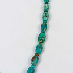 a long necklace with turquoise and gold beads on a white background, the bea is made out of glass