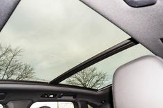 the rear view mirror of a car with trees in the back ground and cloudy sky