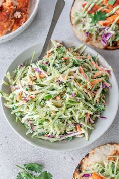 a salad in a white bowl next to two pita bread