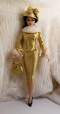 the doll is wearing a gold dress and hat with fur on it's head