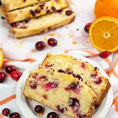 two slices of cranberry orange bread on a plate next to sliced oranges