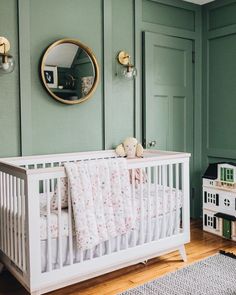 a baby's room with green walls and white crib in the foreground