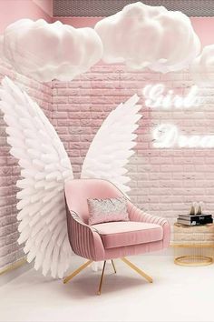 a pink room with angel wings on the wall and two chairs in front of it