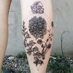 a tattoo on the leg of a woman with flowers and honeycombs in it