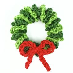 a crocheted christmas wreath with red and green yarn tied around the edges, on a white background