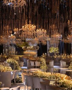 a large room filled with lots of tables covered in white and gold cloths next to tall chandeliers