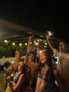 a group of people standing next to each other holding sparklers in their hands and wearing bikinis