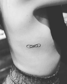 a black and white photo of a woman's stomach with an infinite symbol tattoo on it