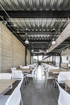 tables and chairs are lined up in an empty room with exposed metal roofing on the walls