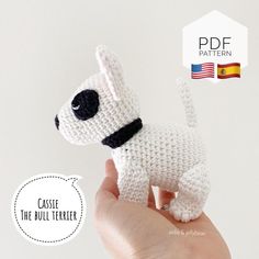 a crocheted white dog with black collar is being held by a person's hand