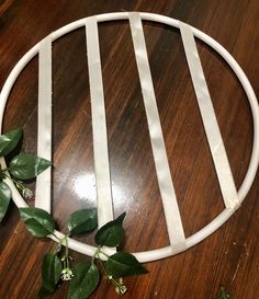 a circle with white strips and green leaves on it sitting on a wooden table top