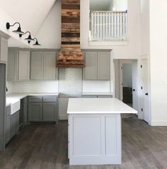 an empty kitchen with white counter tops and gray cabinetry, along with wooden accents