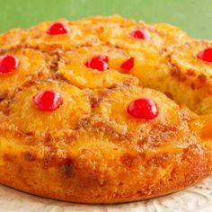 a pineapple upside down cake with cherries on top sitting on a white plate