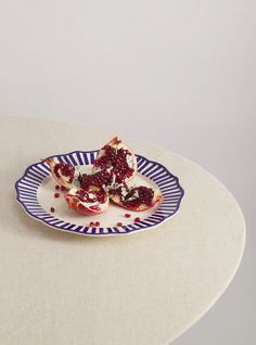 pomegranates on a plate with blue and white stripes sitting on a table