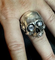 RING PROFILE: 🔱Our Mortis Fleur de Lis silver skull ring is certainly one of the most anatomically accurate and detailed skull rings on the market. We have meticulously created a statement skull ring full of character and personality. Its old and subtly sad-looking expression represents the experience and burden of a human life. 🔱To make this skull ring an even more extraordinary piece we have attached a Fleur-de-Lis on each side of the temple and the word MORTIS wrapped around the ring band t Alexander Mcqueen Skull Ring, Sterling Silver Skull Ring In White Gold, Silver Skull Ring Collectible, Hand Cast Sterling Silver Skull Ring, Sterling Silver Skull Ring Collectible, Collectible Sterling Silver Skull Ring, Collectible Hand Cast Skull Rings, Octopus Jewelry, Skull Rings