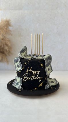 a birthday cake with dollar bills on it and the words happy birthday written in gold