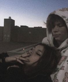 two people standing next to each other in front of a city skyline at night time