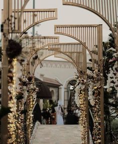 an outdoor wedding ceremony with gold and white flowers on the arch, surrounded by greenery