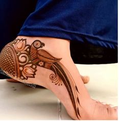 the foot is decorated with henna designs and birds on it's feet,