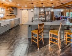 a large kitchen with an island and two wooden chairs in front of the counter top