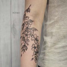 a woman's arm with flowers and leaves tattooed on the left side of her arm