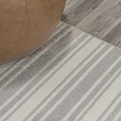 a brown leather chair sitting on top of a wooden floor next to a gray and white rug