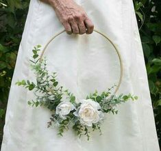 a person holding a white rose and greenery wreath