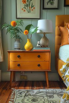 a yellow dresser with two vases and flowers on it