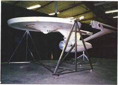 an airplane sitting on top of a metal stand in a garage next to another plane