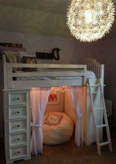 a white bunk bed sitting under a chandelier next to a desk and chair