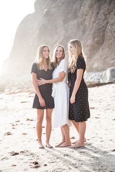 three women standing together on the beach with their arms around each other and smiling at the camera