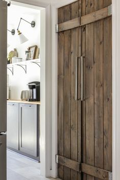 an open door leading to a kitchen with stainless steel appliances and wooden cabinets in it