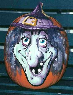 a painted pumpkin with a witch's hat on it, sitting on a bench