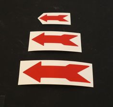 two red arrows pointing in opposite directions on a black surface with white border around them