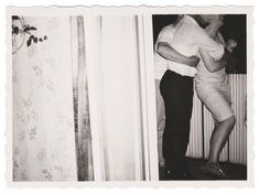 an old black and white photo of two people hugging each other in front of a door