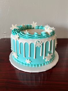 a blue and white frosted cake sitting on top of a wooden table