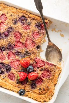 a close up of a plate of food with berries on it and a spoon next to it