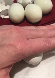 a person's hand next to some eggs on a red cloth and white tablecloth