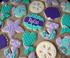 decorated cookies are displayed on a table with purple and blue decorations, including sea shells