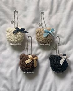 four crocheted purses with bows on them sitting on a white sheet in the shape of hearts