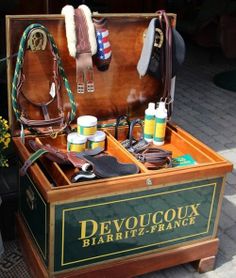 an open wooden box containing several different types of horse tacks and saddleing supplies