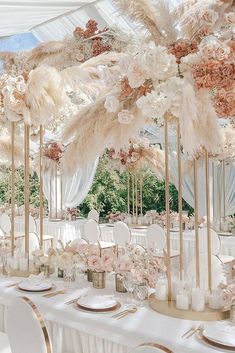 an image of a table set up with flowers and feathers on it for a wedding