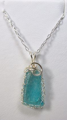 "Beach Glass Necklace, Sea Glass Necklace This is a great item for those who love the beach and its many treasures. A truly unique piece of jewelry. This stunning pendant necklace is made with aqua blue beach glass that is hand -woven with fine gauge silver-plated wire and wrapped with heavier gauge swirl accents.  Measures approximately 1 1/4\" long x 1/2\" wide. Hangs from an 18\" sterling silver chain. Arrives gift boxed. A perfect look for formal and business attire or just for fun! See my o Beach Glass Necklace, Beachglass Jewelry, Sea Glass Pendant, Blue Sea Glass, Blue Beach, Sea Glass Necklace, Pendant Silver, Beach Glass, Silver Filigree