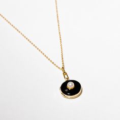 Sleek, sultry, dark — basically Morticia Addams as a necklace. Hold your loved ones (or things) close in this stunning locket. DETAILS- Gold plated sterling silver and black enamel locket with pearl center- Gold plated sterling silver chain- Lobster claw hook- Nickel-free and naturally hypoallergenic- 17.5" chain length + 2" extender Everyday Pendant Locket Necklace, Everyday Locket Pendant Necklace, Sterling Silver Necklace With Yellow Gold And Black Enamel, Sterling Silver Medallion Necklace With Pearl Pendant, Timeless Black Enamel Jewelry As A Gift, Timeless Black Enamel Jewelry As Gift, Timeless Black Enamel Jewelry For Gifts, Timeless Black Enamel Jewelry Gift, Everyday Black Enamel Jewelry