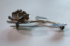 "The past will always return in the fashion world and this piece is back for round two! In the 1920's ladies of class wore the most opulent dresses with jewelry to match. As the years continued, jewelry makers tailored pieces to fashion and trends which resulted in affordability for style. Presenting this Beautiful Vintage Ladies Sterling Silver Long Stem Rose Brooch Pin Featuring Highly Detailed Designs. Approximate Size: 2.00\" long Don't forget to LIKE ☑️ us on Facebook for FREE coupon codes Rose Colored Formal Brooches, Elegant Rose Design Brooches For Anniversary, Elegant Formal Brooch With Rose Design, Elegant Formal Rose Design Brooches, Elegant Formal Rose Design Brooch, Engraved Silver Oval Brooches, Luxury Vintage Silver Pins, Vintage Silver Flower Pins, Vintage Sterling Silver Flower Brooches