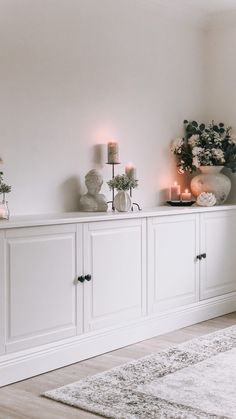 a living room with white furniture and candles