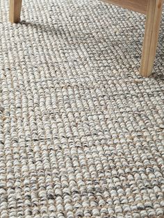 a wooden bench sitting on top of a carpeted floor next to a white rug