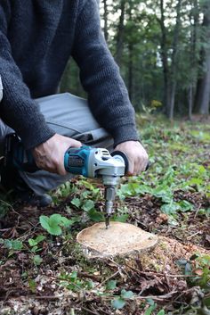 a man using a drill to cut wood in the woods